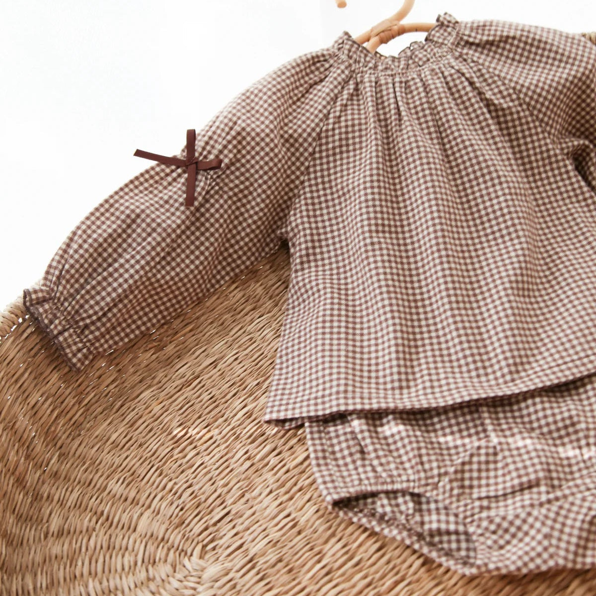 Brown checkered baby outfit with top and bloomers on a hanger against a white background
