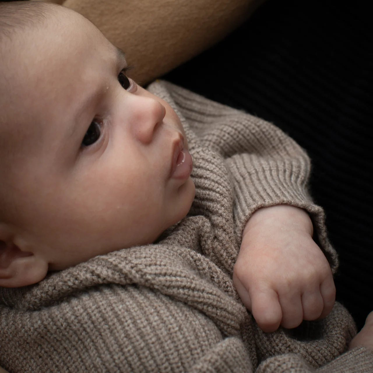 Close-up of a baby wrapped in a brown blanket with a blurred background