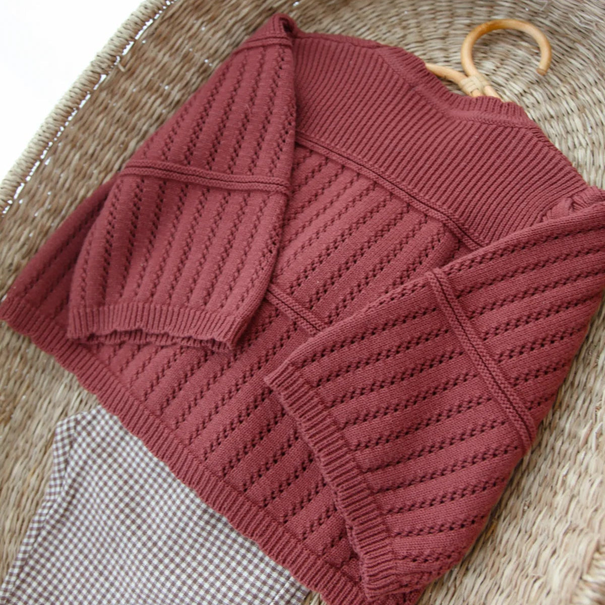 Knitted sweater on a wooden hanger against a woven basket background
